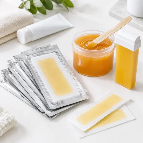 Pre-coated wax strip foil packaging with a jar of soft wax and roll-on cartridge on a white surface